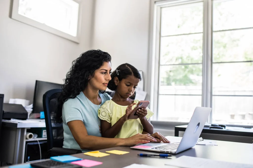 A mom working on laptop with her daughter